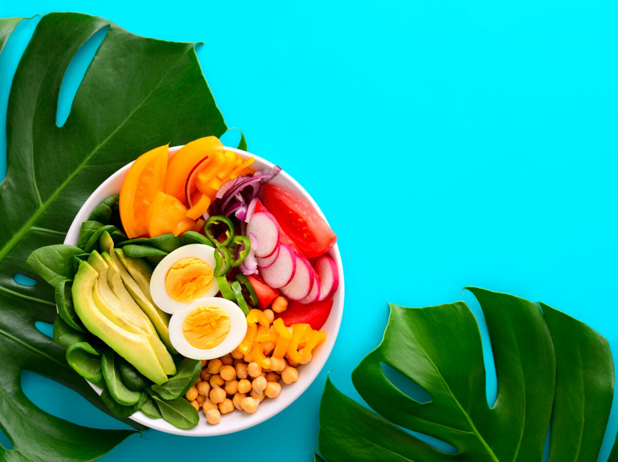 Freshly cooked Buddha bowl salad served on summer style decorated table, view from above, blank space for a text